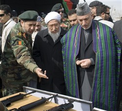 Afghan President Hamid Karzai (right) looks over weapons