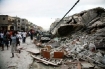 Haitians walk past damaged buildings on January 12 in Port-au-Prince