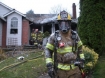 A firefighter covered in foam exits the house after dousing hot spots