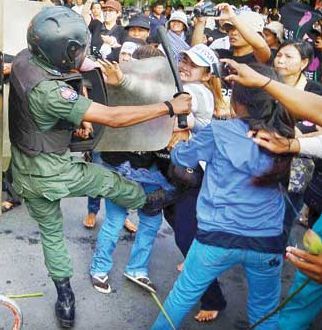 Bov Sreyros (in white hat) is kicked by a police officer 