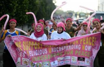 Muslim women hold a banner as they run during an event called 